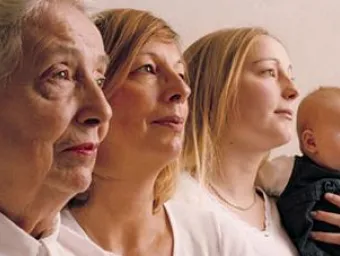 Four people at different stages in their lives, side by side, looking ahead, out of the frame of the photo. There is a newborn and their parent, a middle aged person, and, in the foreground, an older person